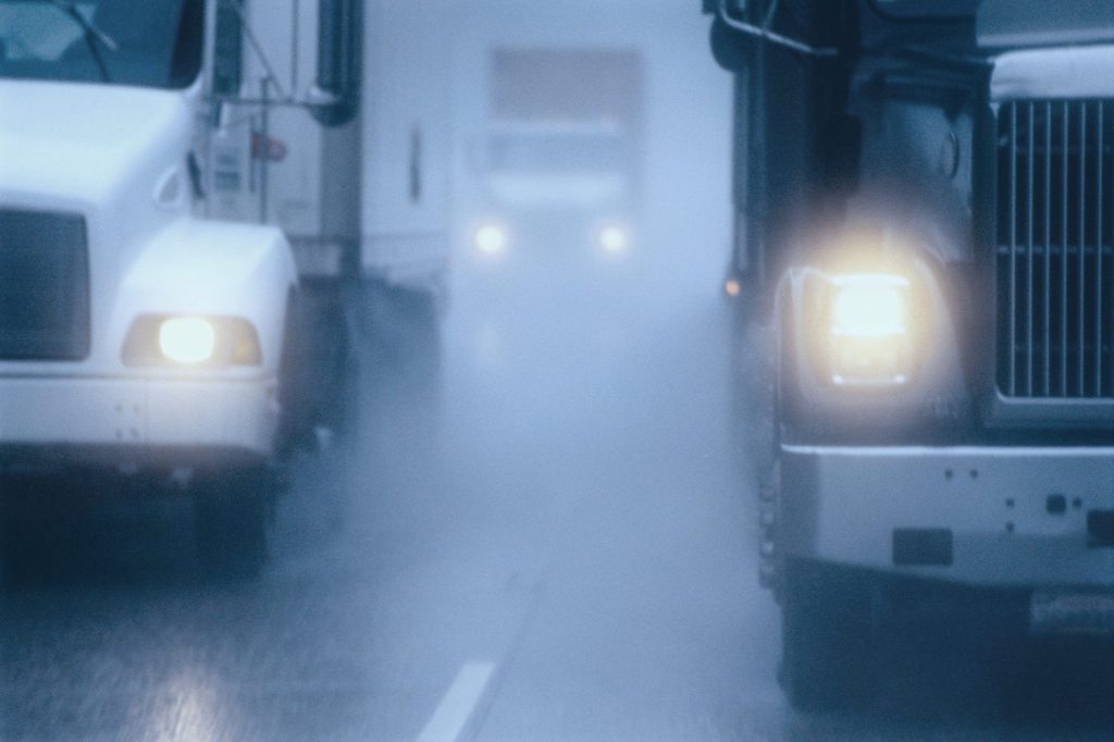 A truck driving down the street in heavy rain.